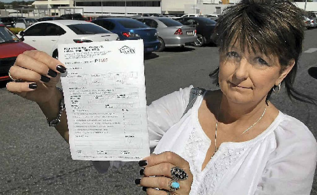 Sher Hennessy holds up her son’s parking ticket outside Rockhampton Hospital. Sher Hennessy holds up her son’s parking ticket outside Rockhampton Hospital.